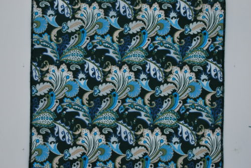 Plan rapproché du tissu de la série Miami, un coton vert foncé avec un motif cachemire bleu turquoise, beige et blanc.